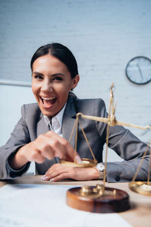 selective focus of excited businesswoman in formal wear touching scales in office