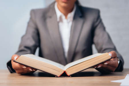 selective focus of lawyer in suit reading book in officeの写真素材
