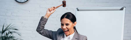panoramic shot of excited judge holding gavel near documents