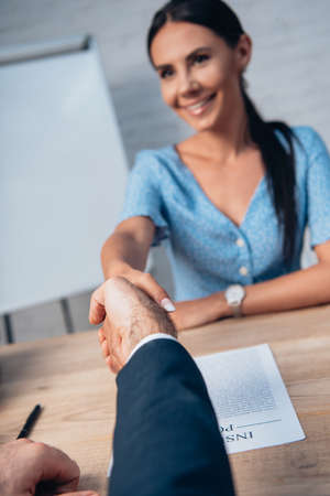 selective focus of brunette woman and lawyer shaking hands in officeの写真素材