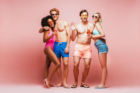 shirtless man waving hand while looking at camera together with multicultural friends holding...