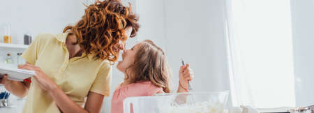 selective focus of mother standing face to face with daughter kneading dough in kitchenの写真素材