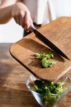 cropped view of woman adding broccoli in bowlの写真素材