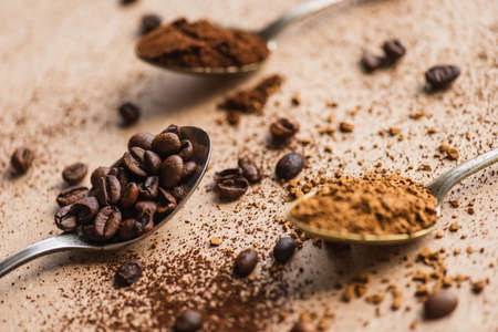 selective focus of ground, instant coffee and beans in spoons on beige surfaceの写真素材