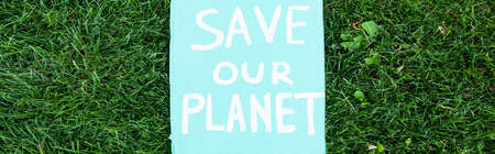 Horizontal concept of placard with save our planet lettering on grass, ecology concept