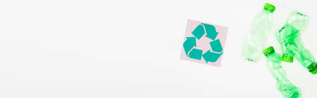 Horizontal crop of crumpled plastic bottles near card with recycle symbol on white background, ecology conceptの写真素材