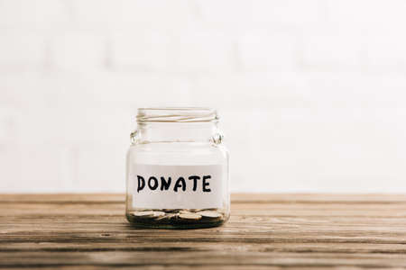 penny jar with donate lettering on wooden surface on white backgroundの写真素材