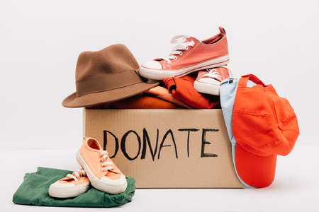 cardboard box with donated accessories, clothes and footwear isolated on white, charity conceptの写真素材