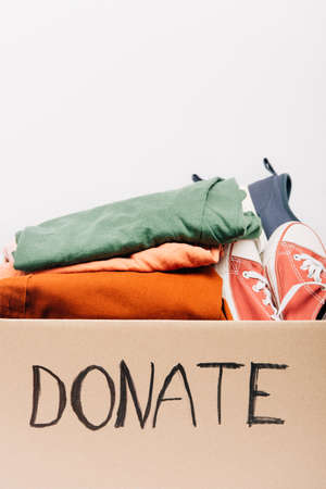 cardboard box with donated clothes and footwear isolated on white, charity concept