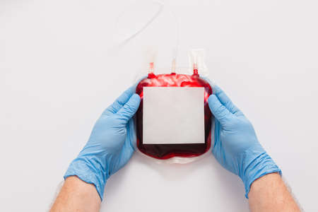 cropped view of doctor holding blood donation package with blank label on white backgroundの写真素材