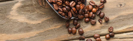 top view of metal scoop with coffee beans on wooden surface, panoramic shotの写真素材