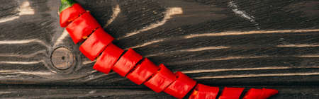 top view of sliced red chili pepper on wooden surface, panoramic shotの写真素材