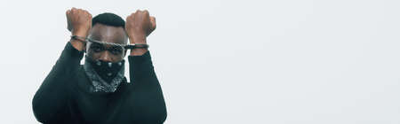 panoramic shot of handcuffed african american man looking at camera isolated on white, racism...