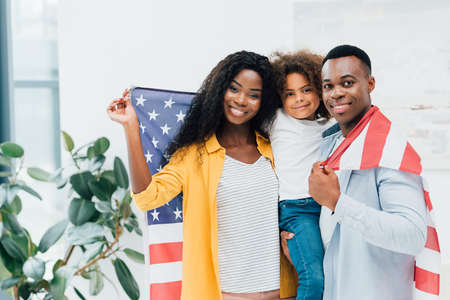 african american family holding flag of america and looking at camera