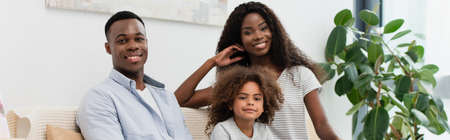 panoramic shot of african american family looking at camera in living room