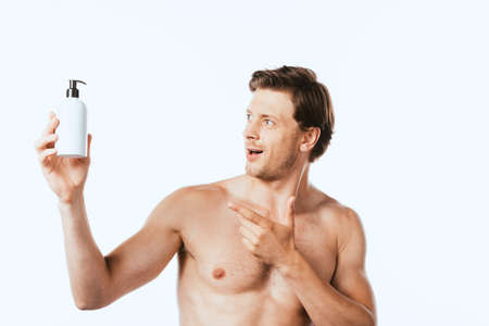 Shirtless man pointing at bottle of lotion isolated on whiteの写真素材