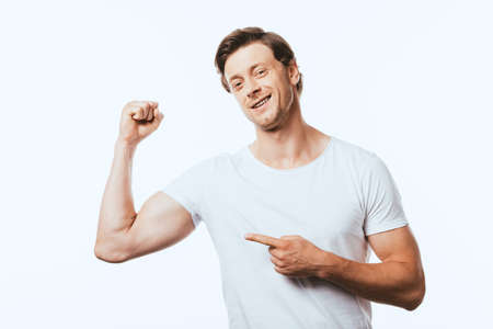 Young man pointing with finger at muscles on hand isolated on white