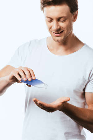 Man in white t-shirt pouring toner in hand isolated on white