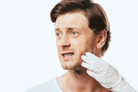 Dermatologist in latex glove touching cheek of patient isolated on whiteの写真素材