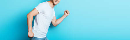 Panoramic crop of man in white t-shirt on blue background