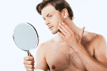 Shirtless man touching skin while holding mirror isolated on whiteの写真素材