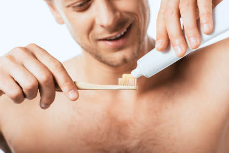Cropped view of shirtless man holding toothbrush and toothpaste isolated on whiteの写真素材