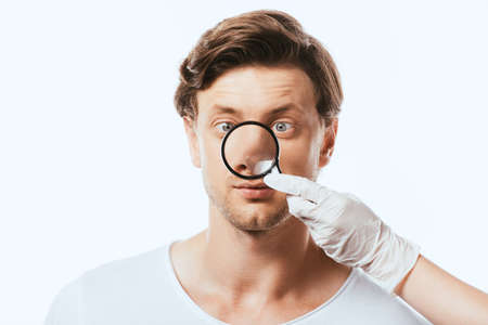 Dermatologist in latex glove holding loupe near nose of patient isolated on white