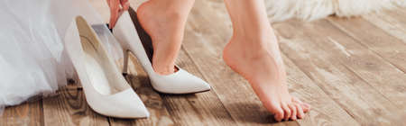 Panoramic crop of bride putting on white heels at homeの写真素材