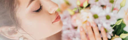 Panoramic shot of bride touching flowers in bouquet