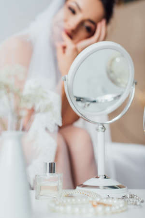 Selective focus of accessories, mirror and bottle of perfume on coffee table near bride at homeの写真素材