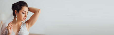 Panoramic crop of brunette bride in wedding dress touching veilの写真素材