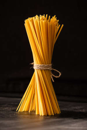 tied uncooked Italian spaghetti isolated on blackの写真素材