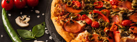 delicious Italian pizza with salami near vegetables on black background, panoramic shotの写真素材