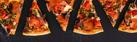 top view of delicious Italian pizza slices with vegetables and salami on black background, panoramic...