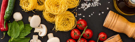 top view of raw Italian Capellini with vegetables and seasoning on black background, panoramic shotの写真素材