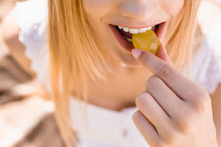 partial view of young woman eating ripe grape, selective focusの写真素材