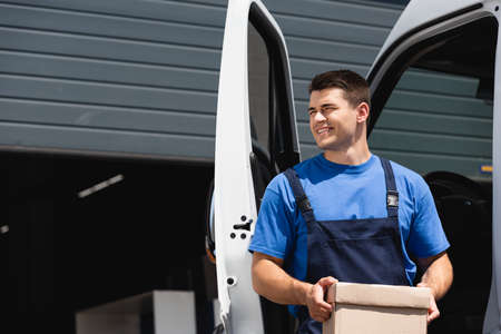 Loader holding cardboard box and looking away near truck outdoorsの写真素材