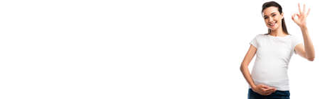 panoramic concept of pregnant woman in white t-shirt touching belly and showing ok sign isolated on...