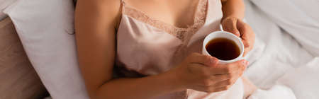 panoramic crop of woman holding cup of tea