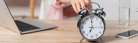 panoramic crop of retro alarm clock near freelancer and gadgets on table