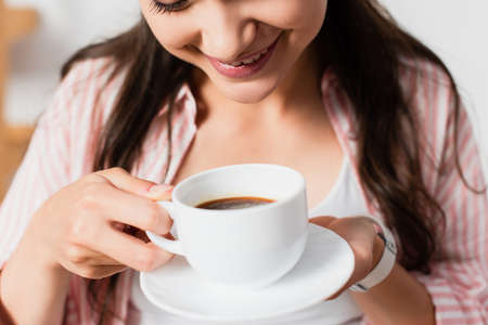 cropped view of young woman holding cup of coffee