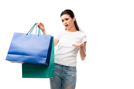 young displeased woman looking at shopping bags isolated on whiteの写真素材