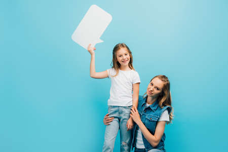 mother squatting near child wearing white t-shirt and jeans and holding speech bubble isolated on...