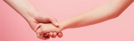 cropped view of woman and child holding hands isolated on pink, website header