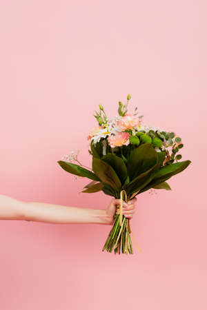 cropped view of woman holding bouquet of flowers isolated on pinkの写真素材