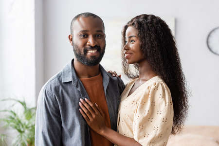 young african american woman touching husband looking at camera at homeの写真素材