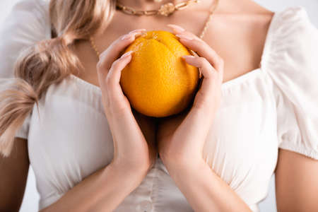 cropped view of elegant blonde woman holding orangeの写真素材