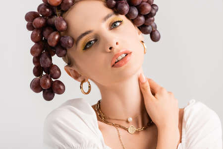 portrait of rustic blonde woman posing with grapes on head isolated on whiteの写真素材