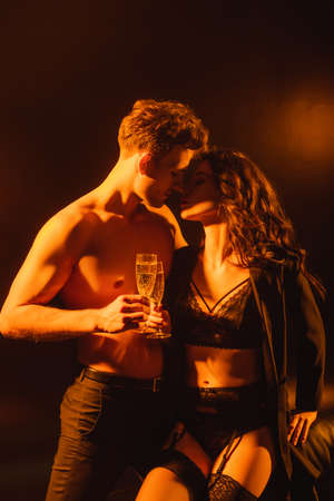 sexy couple with closed eyes holding glasses with champagne while clinking on blackの写真素材