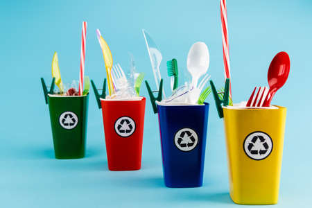 multicolored recycling bins with plastic on blue background